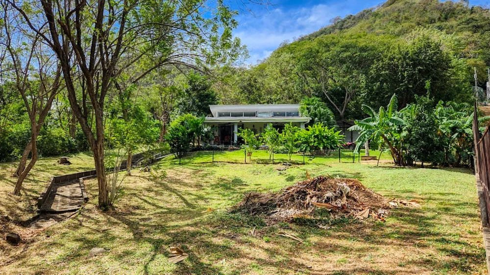 One-bedroom home on 2,900 square meter (¾ acre) lot in Las Delicias near San Juan del Sur with tropical gardens, fruit trees, covered parking, and dual water supply.