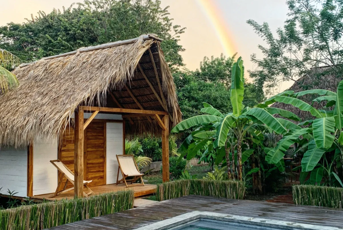 Rainbow over a wooden bungalow and tropical garden at Monoloko Lodge, a surf lodge for sale near Playa Santana, Popoyo, Nicaragua