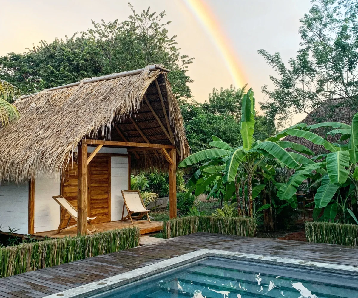 Rainbow over a wooden bungalow and tropical garden at Monoloko Lodge, a surf lodge for sale near Playa Santana, Popoyo, Nicaragua