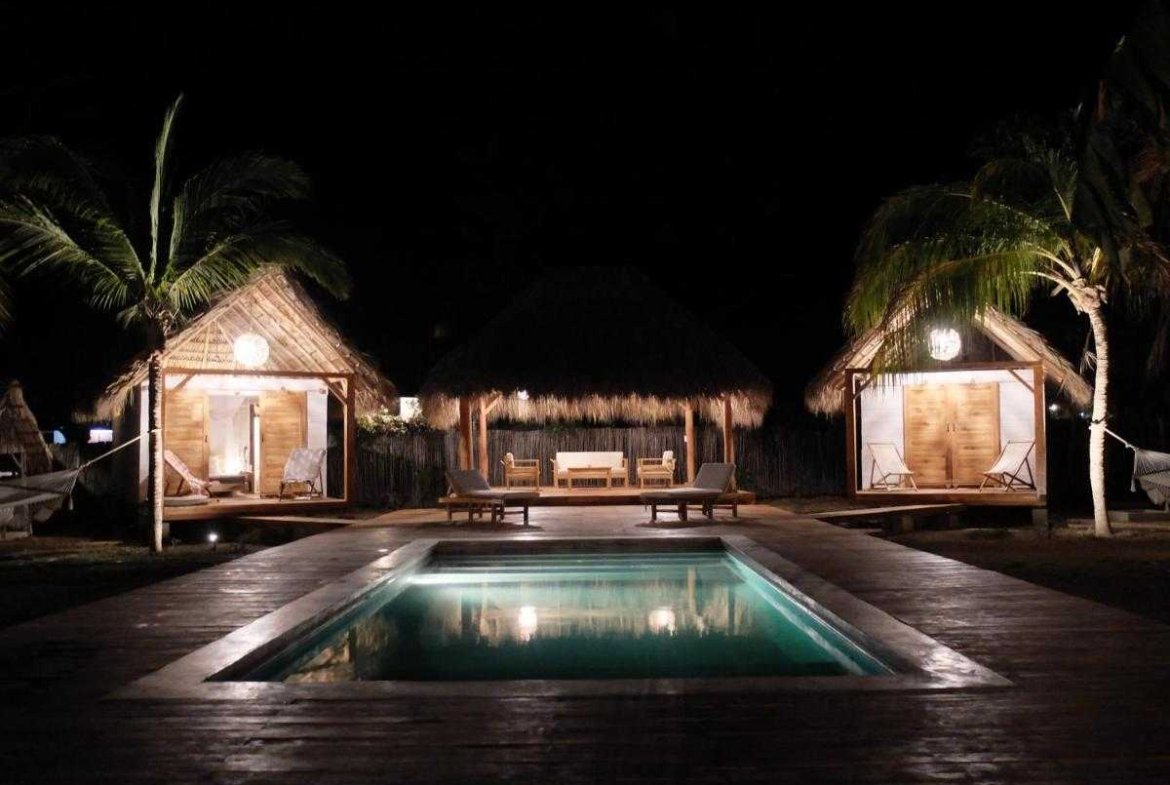 Illuminated pool and bungalows at night at Monoloko Lodge boutique surf retreat, Tola, Nicaragua