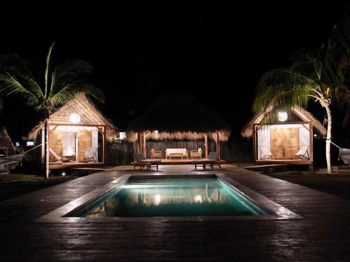 Illuminated pool and bungalows at night at Monoloko Lodge boutique surf retreat, Tola, Nicaragua