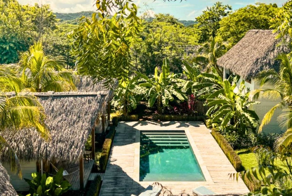 Swimming pool surrounded by tropical gardens at Monoloko Lodge, a surf lodge for sale near Playa Santana, Nicaragua